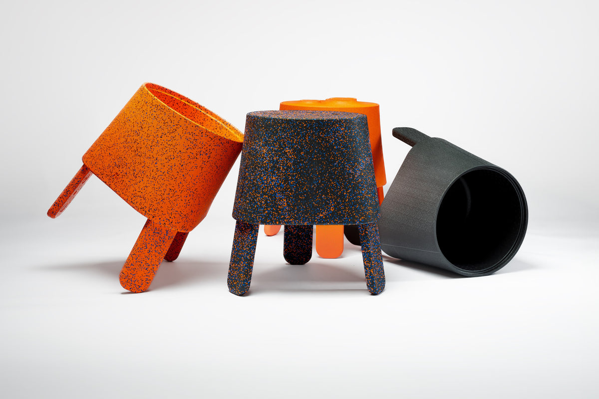 Three AYTO multifunctional side tables in Orange Mix, Black Mix and Black on a light background, one tipped on its side